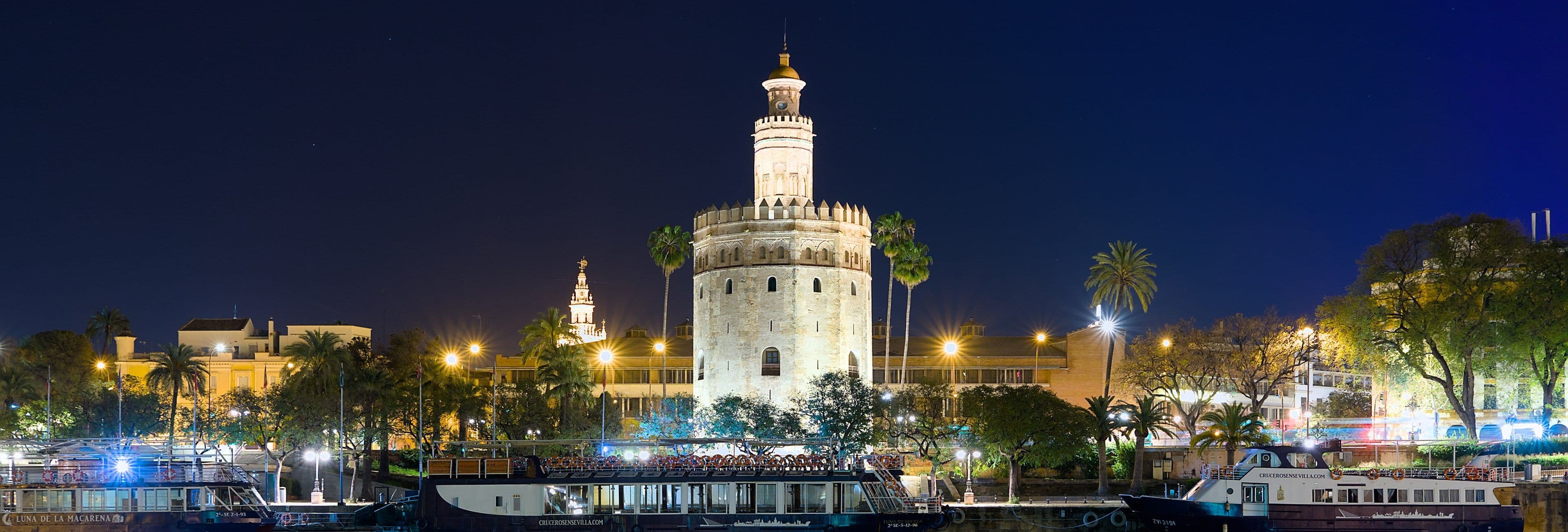 La Torre del Oro iluminada de noche, junto al Guadalquivir, en Sevilla